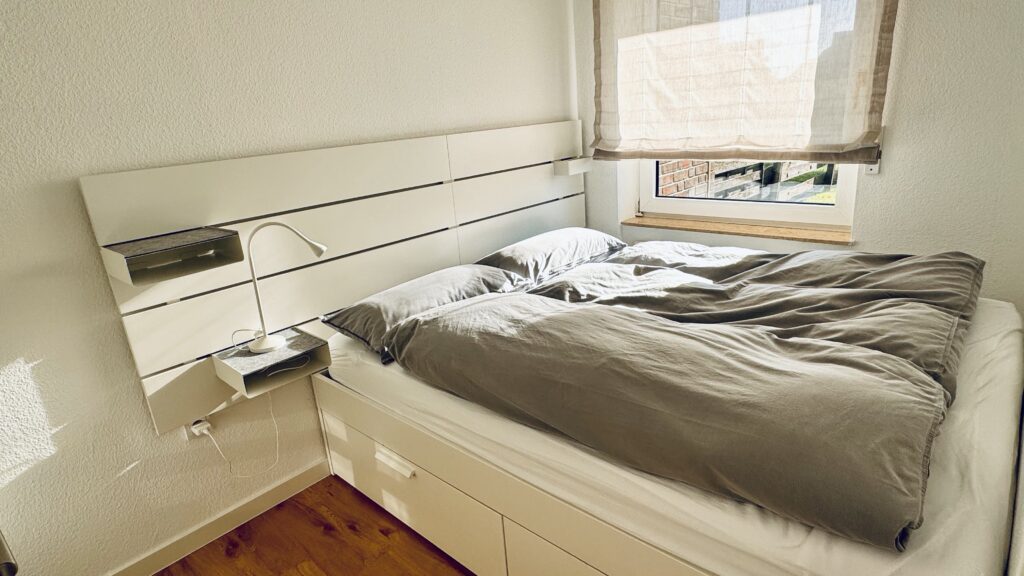 1. Schlafzimmer mit Doppelbett und Nachttisch. Links am Bett steht eine Nachttischlampe.