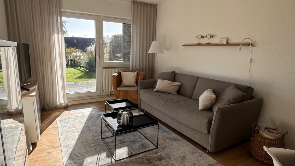 Wohnzimmer der Ferienwohnung mit Schlafsofa. Über die Terrassentür gelangt man in den zum Garten.