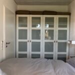 1. Schlafzimmer mit Doppelbett. Im Hintergrund steht ein großer Kleiderschrank in weiß.