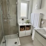 Barrierearmes Badezimmer mit ebenerdigem Einstieg in die Dusche und praktischen Badaccessoires wie Kosmetikspiegel.
