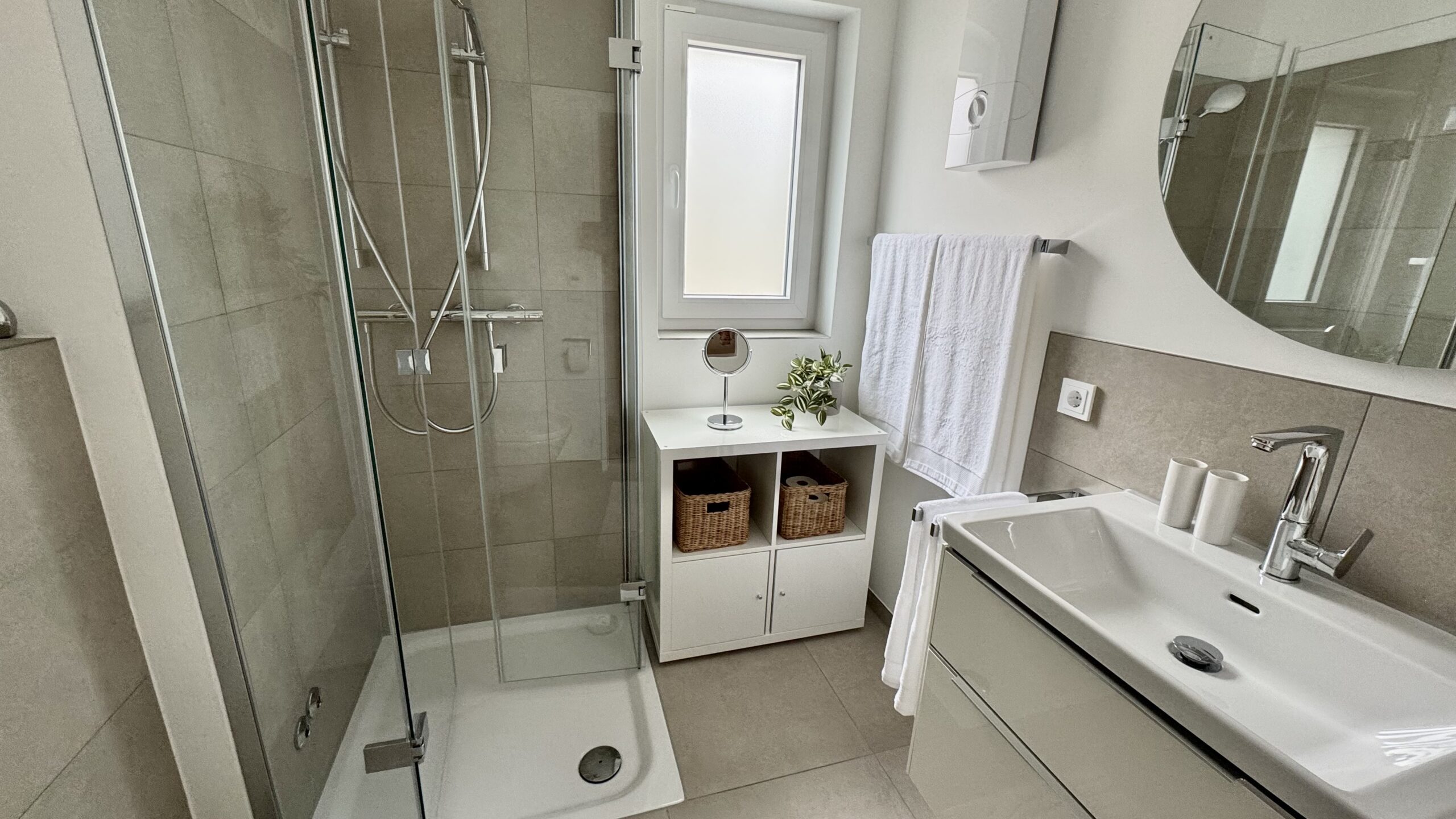Barrierearmes Badezimmer mit ebenerdigem Einstieg in die Dusche und praktischen Badaccessoires wie Kosmetikspiegel.